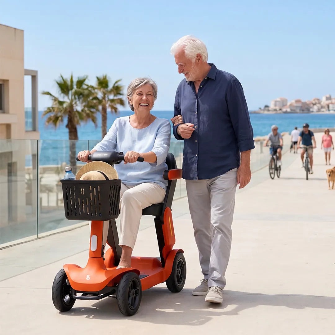 Pareja de personas mayores utilizando el scooter para la movilidad por el paseo marítimo de la ciudad dortomedical