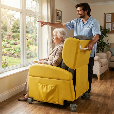 Mujer mayor en su sillón junto a un cuidador; la movilidad de las ruedas permite situar el sillón fácilmente en lugares con luz natural y vistas al exterior dortomedical