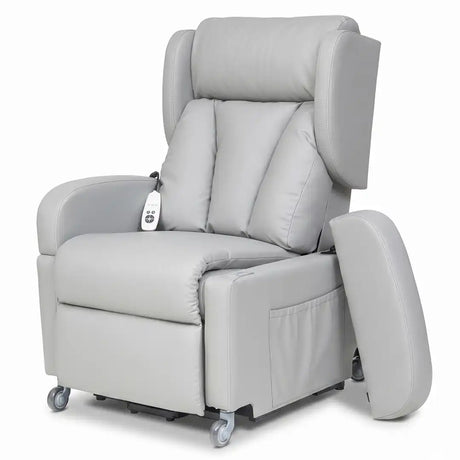 Vista frontal del sillón con el reposabrazos extraído y apoyado en el suelo, mostrando cómo se libera el lateral para realizar transferencias cómodas a sillas de ruedas o camas dortomedical